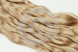 Light brown wavy human hair on white background. Beauty salon. Hair Extensions.