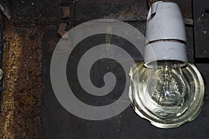 Light bulb on the background of old rusty iron, reflector cover from the can.