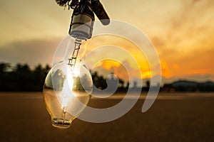 Light bulb on the beach and mountain background,lamp light with sunset,energy conceptLight bulb on the beach and mountain