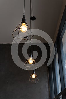 Light bulb in black steel cage hang on ceiling in coffee shop