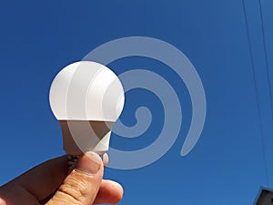 light bulb on blue sky background in human hand. Electricity concept. Saving electricity