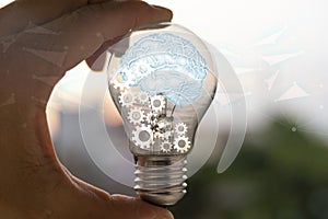 Light bulb with brain inside the hands of the businessman