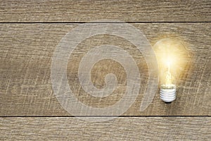 Light bulb with bright light on plank wood background. Simple and inspiration are origins of thinking innovative technology.