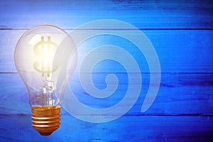 Light bulb with Dollar symbolon blue wooden background. Money ma