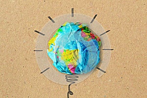 Light bulb drawing and planet earth on crumpled recycled paper - Concept of ecology and green energy innovation