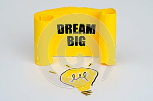 A light bulb is drawn on a white background, next to it is a yellow plate with the inscription - Dream Big