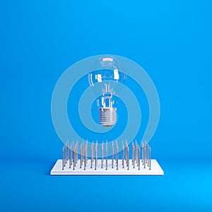 Light bulb floating above nail traps on blue background color