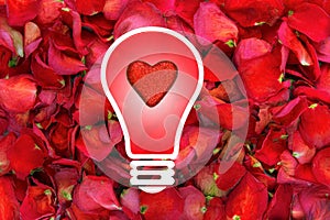 Light bulb with glitter heart in centre on dried rose petal background