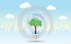 Light bulb with green tree inside in city buildings and blue sky background.