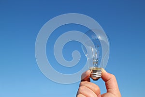 Light bulb and the hand in the blue sky