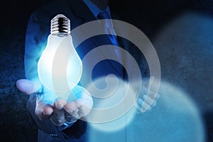 Light bulb in hand businessman on blue tone