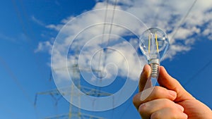 Light bulb in hand on Pylon of the electricity power line background.Electricity concept. electricity line. Power lines