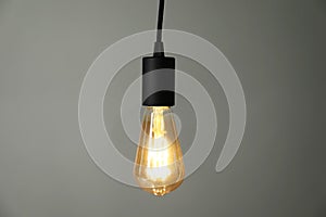 Light bulb hanging on cord against grey background