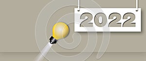 Light bulb hitting to the year 2022 on grey background. Concept for innovative business vision or resolution.