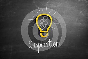 Light bulb icon and inspiration text on blackboard