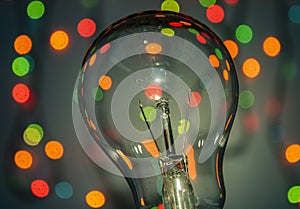 Light bulb on multicolored lights background.