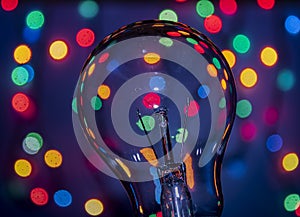 Light bulb on multicolored lights background.