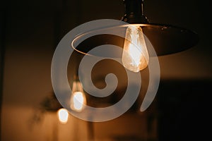 Light bulb Orange incandescent lamp hanging in low light