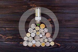 light bulb on over pile of coins - money, finance, savings concept and idea