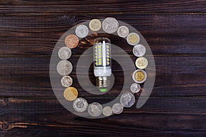 light bulb on over pile of coins - money, finance, savings concept and idea
