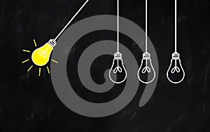 Light bulb pendulum. Creativity concept with light lamp on a rustic blackboard