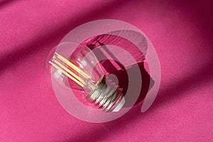 Light bulb on purple background with shadows close up. Creative new idea, innovation, inspiration concept.