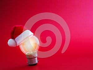 Light bulb and Santa Claus hat over red background with copy space