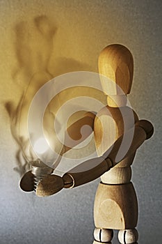 a light bulb shines in the hands of the wooden figure, the warmth of the bulb makes the wood of the doll smoke