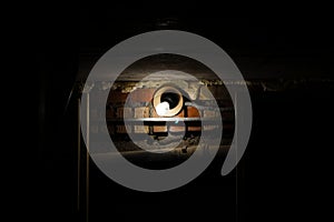 A light bulb shines on an old brick wall in a dark room