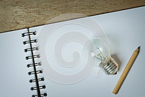 Light Bulb with a Small Pencil Placed on an Opened Sketchbook