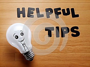 A light bulb with a smiling face drawn on it, next to the text words helpful tips