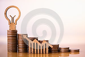 Light bulb and stack of coins in concept of savings and money growing or energy save.