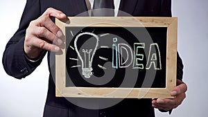 Light bulb, symbol of idea written on blackboard, man holding sign, motivation