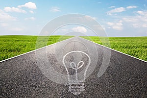 Light bulb symbol on long empty straight road