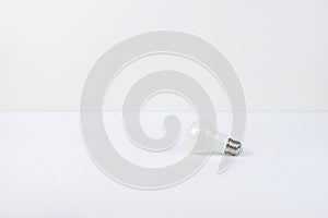 Light Bulb on White Surface with Bright Background