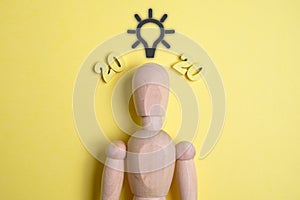 A light bulb will glow near a wooden dummy and figures 2020 in the new year on a yellow background. Concept idea