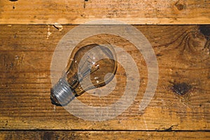 Light bulb on a wooden background. old glass lamp lies on the table