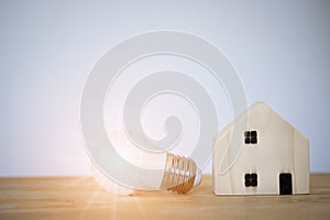 Light bulb with wooden home on table, power energy, save, new idea, new business, mortgage, property, new house and technology