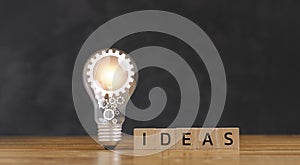 Light bulb on wooden table and wood block with Word Ideas, new idea concept with innovation and inspiration