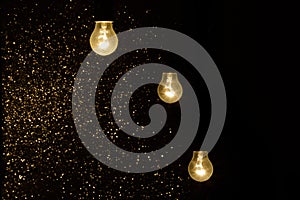 Light bulbs on a black background with sparkles