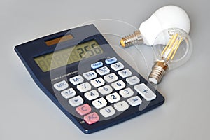 Light bulbs and calculator on gray background, close-up. Concept for Energy price increase