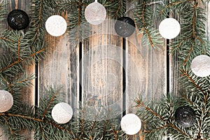 Light bulbs Christmas tree branches and balls garland frame on rustic gray plank surface. Holiday background, copy space