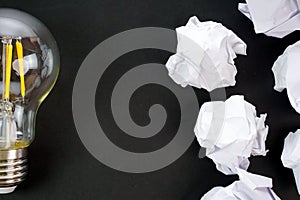 Light bulbs and crumpled paper on black background. Good idea and creativity concept.