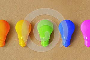 Light bulbs in different colors on recycled paper background - Concept of creativity and divergent thinking