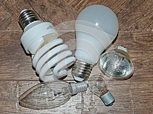 Light bulbs with different light and electrical characteristics on a wooden table.