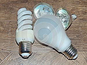 Light bulbs with different light and electrical characteristics on a wooden table.