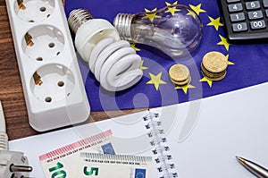 Light Bulbs on european banknotes with empty notepad and pen, calculator