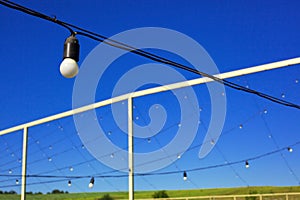 Light bulbs hanging in the row, blue sky, green lawn