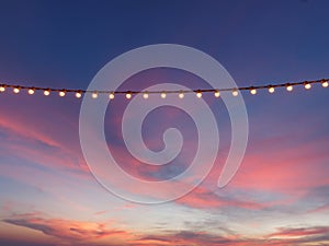 Light bulbs on string wire against sunset sky