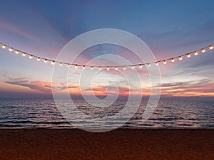 Light bulbs on string wire against sunset sky